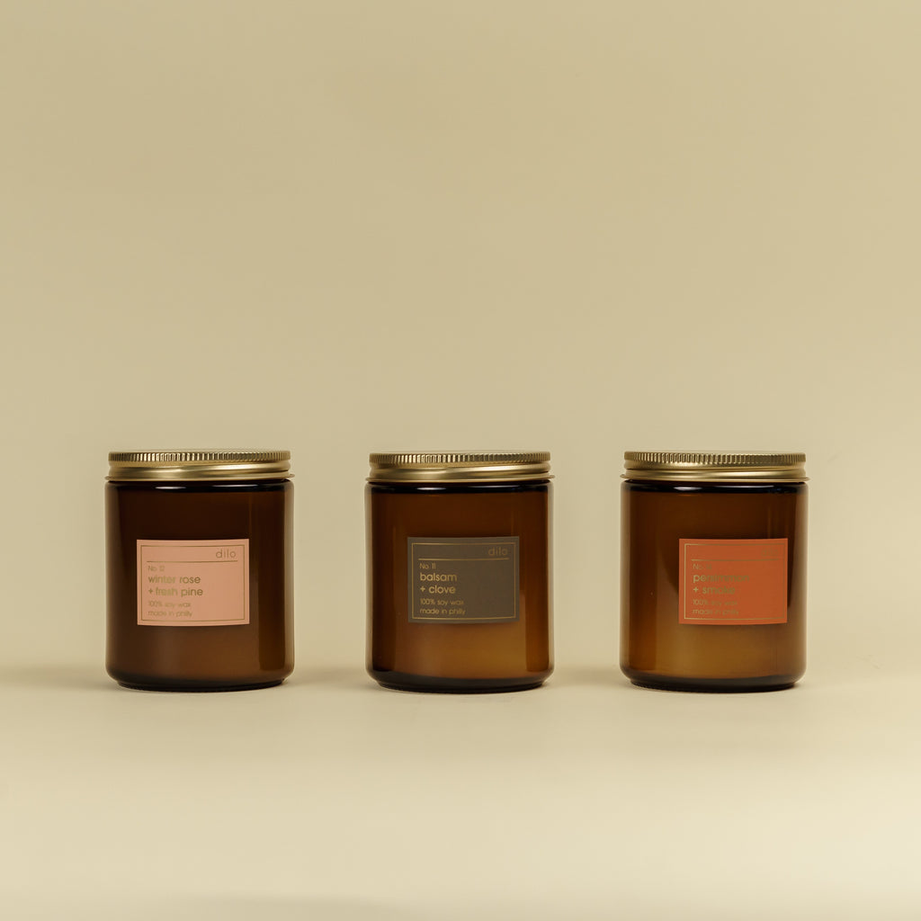 Three brown jar candles with gold lids on a beige background